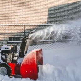 Image of a red snow blower being used by a snow removal service.